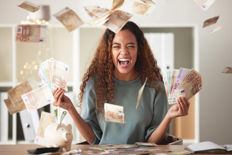 Happy mixed race young woman feeling rich and successful while throwing money at home.  Excited Hispanic man celebrating after saving and budgeting finances.  Planning for the future or win the lottery