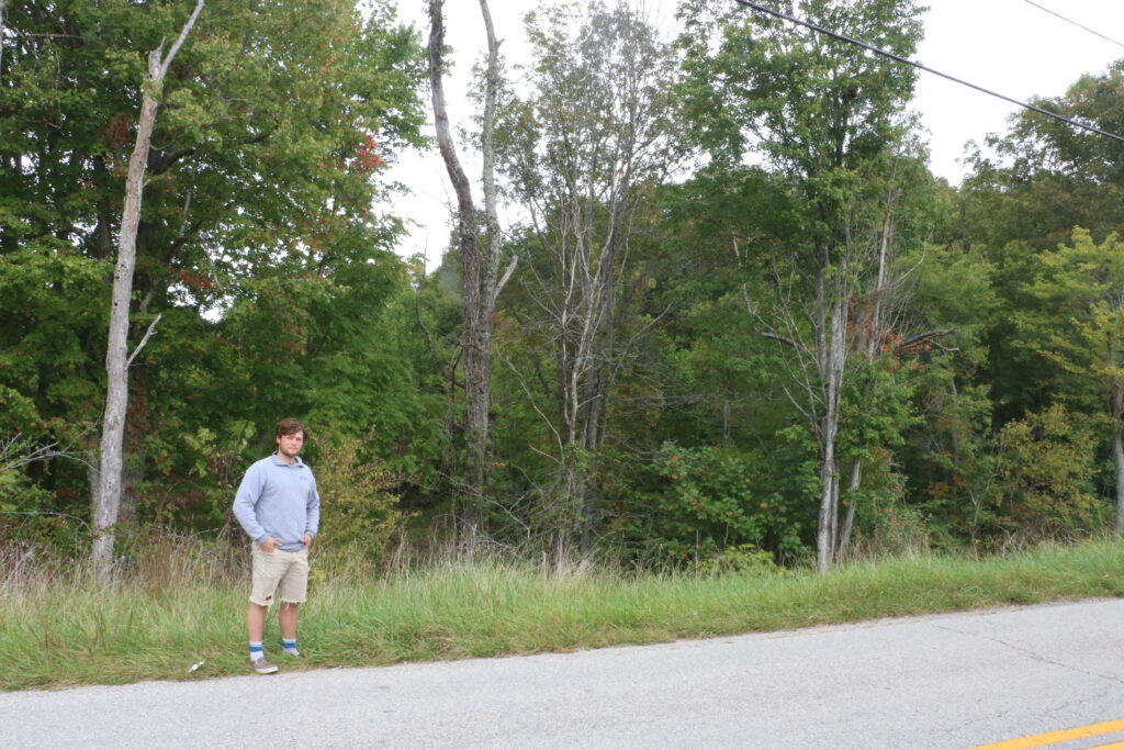 Corey Mattingly poses on the side of the road nearby the Artemis Power Tech facility. Trees cover the site from being seen.