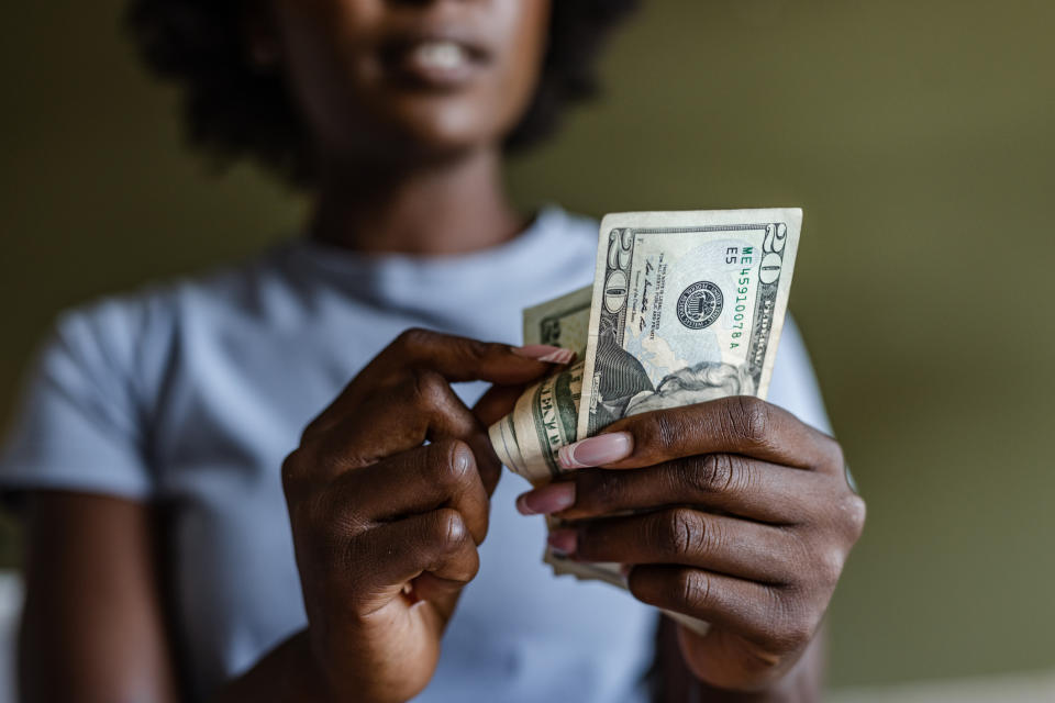 Person counting a stack of US dollar bills with a focused expression, highlighting a financial concept