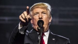 PHUN stock A close-up of Donald Trump behind a microphone with one arm outstretched.