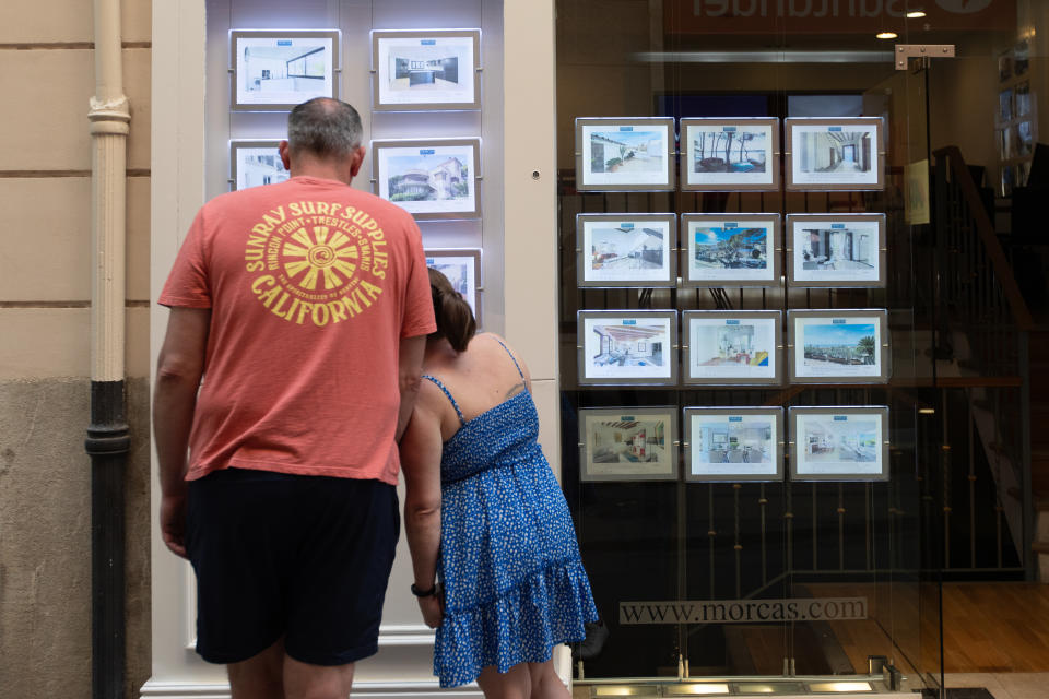 PALMA DE MALLORCA, MAJORCA BALE, SPAIN - APRIL 24: Two people look at advertisements of houses for sale at a real estate agency on April 16, 2024 in Palma de Mallorca, Mallorca, Balearic Islands, Spain. On April 16, the Plenary of the Parliament of the Balearic Islands approved a law, resulting from Decree Law 6/2023 of October 2 on urgent housing measures, which introduced measures to encourage new housing to come on the market in urban areas of municipalities in the Balearic Islands. The Official Association of Real Estate Agents of the Balearic Islands (COAPI) and the Balearic real estate alliance ABINI celebrated the approval. (Photo by Tomas Moya/Europa Press via Getty Images)