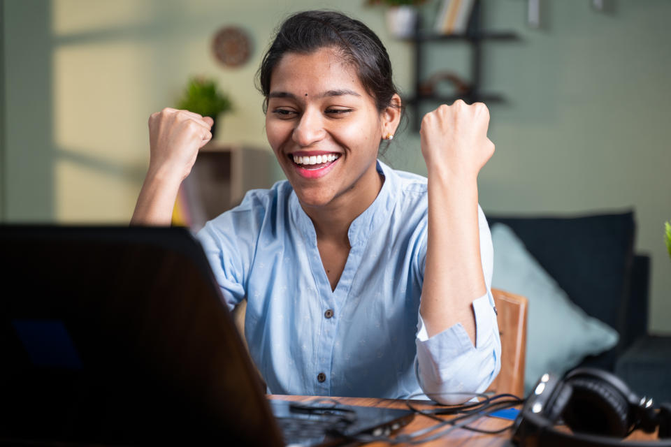 young businesswoman was very happy with good news and started celebrating while working on laptop - Concept of new job offer or promotion, college admission and loan approval or won cash price