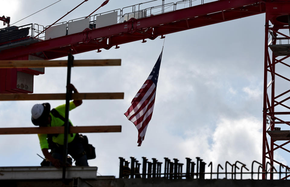 LOS ANGELES, CALIFORNIA - JANUARY 25: An American flag flies from a crane as a construction worker helps build a mixed-use apartment complex that will accommodate more than 700 apartment units and 95,000 square feet of commercial space on January 25. January 2024 in Los Angeles, California.  Department of Commerce economic data released today showed that the US economy expanded 3.1% in 2023, allaying inflation fears and making the US the fastest-growing advanced economy in the world in 2023. (Photo by Mario Tama/Getty Images)