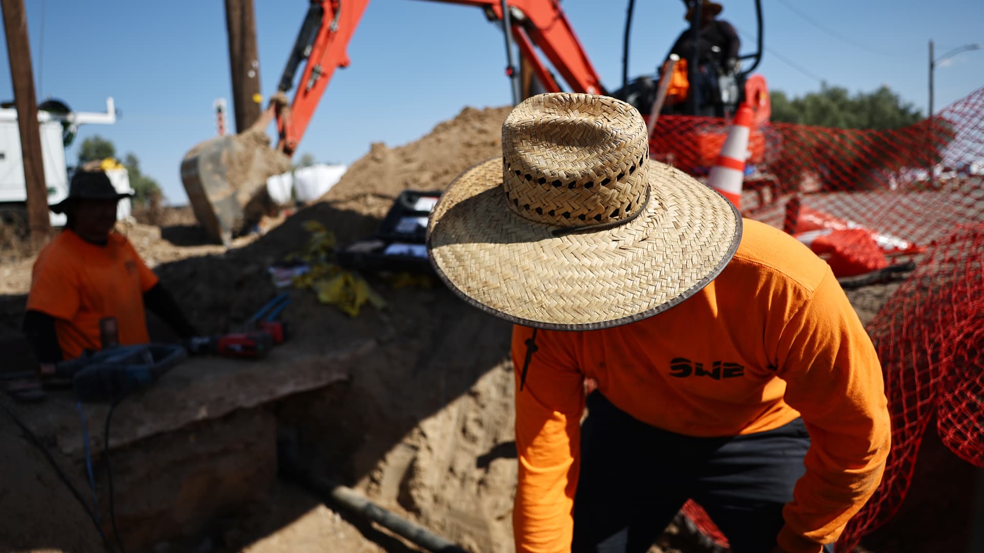 Workers stand in the afternoon heat in Baker, California, on July 10, 2024. A long-lasting heat wave has caused many California cities to break all-time heat records, while several wildfires have sparked across the state.