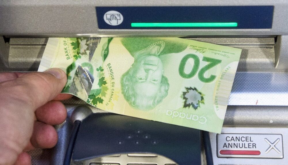 Money is removed from a bank machine in a photo illustration in Montreal, Monday, May 30, 2016. (Ryan Remiorz/The Canadian Press)