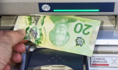 Money is removed from a bank machine in a photo illustration in Montreal, Monday, May 30, 2016. (Ryan Remiorz/The Canadian Press)