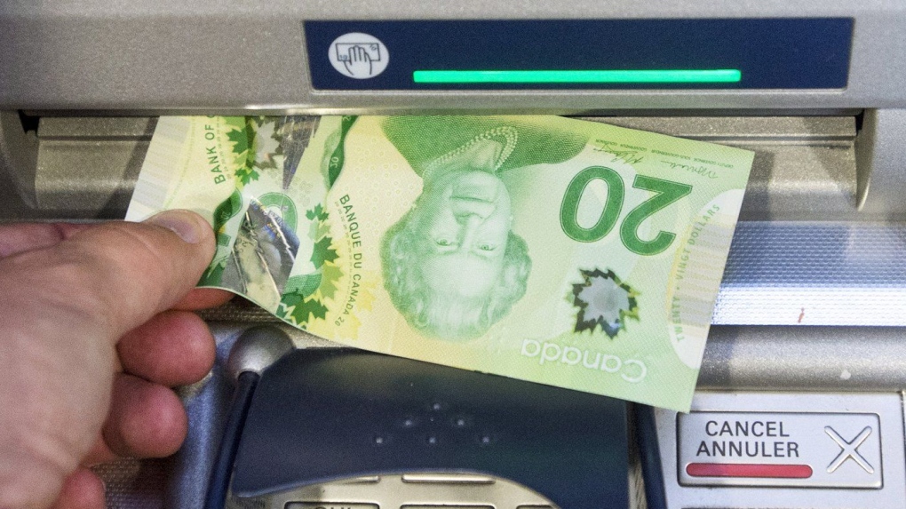 Money is removed from a bank machine in a photo illustration in Montreal, Monday, May 30, 2016. (Ryan Remiorz/The Canadian Press)