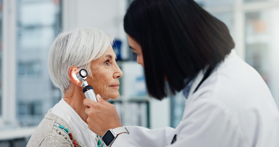 Senior woman doctor and otoscope for ear, hearing test and examination, audio check or consultation for medical care. Ent, ENT and medical professional with senior person for wellness in hospital