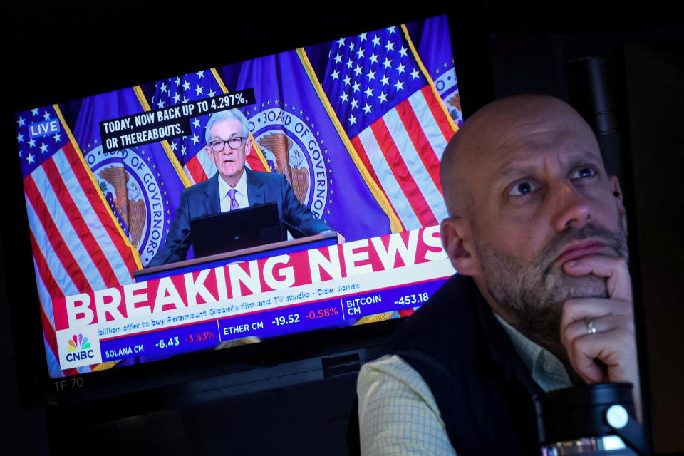 FILE PHOTO: A trader works as a screen broadcasts a news conference by U.S. Federal Reserve Chairman Jerome Powell following the Fed's rate announcement, on the floor of the New York Stock Exchange (NYSE) in New York City, U.S., March 20, 2024. REUTERS/Brendan McDermid/File Photo