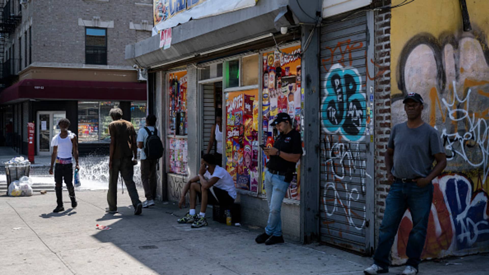 People stand outside a bodega during a summer heat wave in the Bronx borough of New York City on July 11, 2024. 