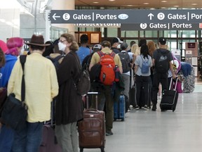 People line up before entering the security zone at Pearson International Airport in Toronto on August 5, 2022.